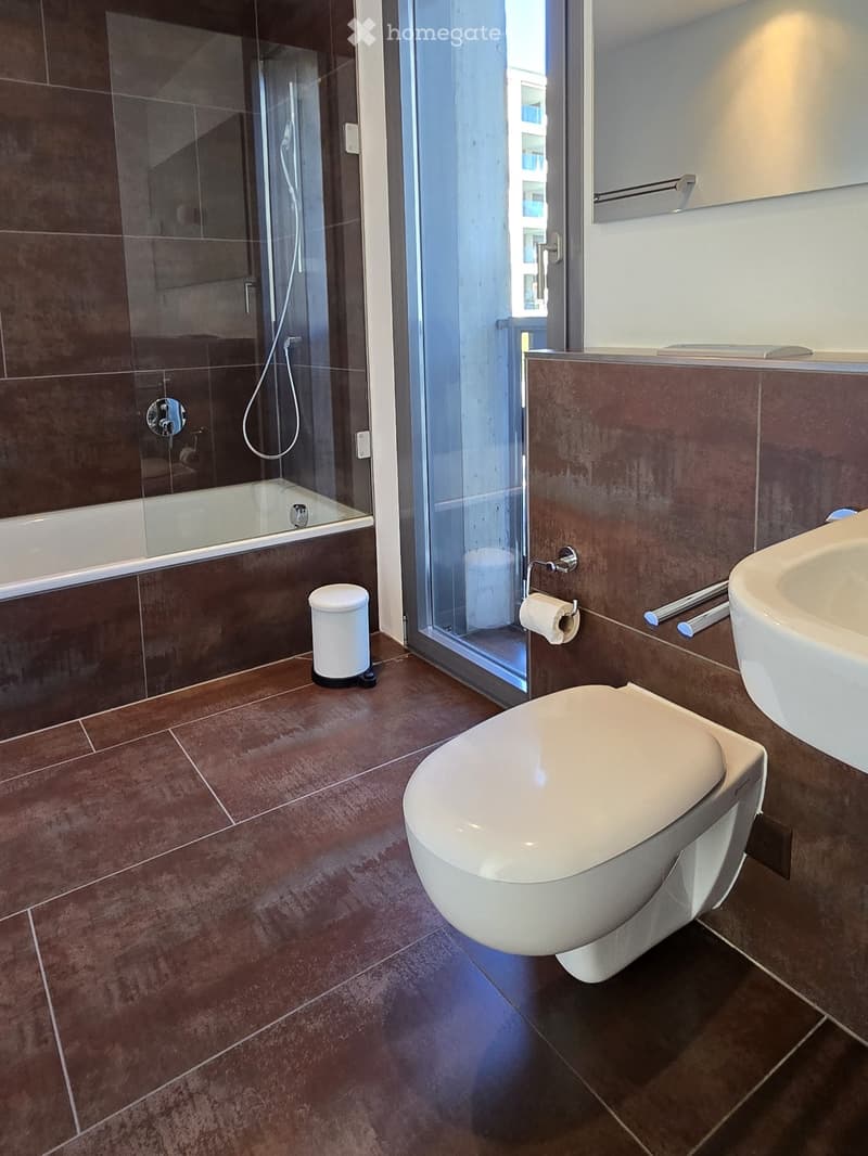modern bathroom with brown tiles, bathtub, toilet, sink, mirror, glass door, showerhead