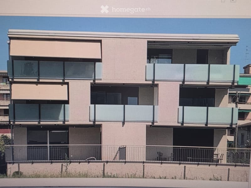 Modern multi-story residential building with balconies, large windows, and a clean, contemporary design.