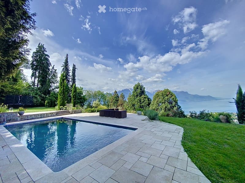 Rectangular swimming pool, brick pathway, brown wooden bench, well-maintained garden, greenery, plants, lake and mountain view