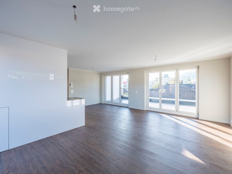 Empty room with wooden flooring, white walls, and large glass doors leading to a balcony.