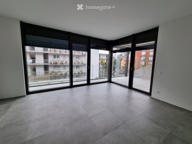 Empty room with large sliding glass doors leading to a balcony, tiled floor, and modern interior design.
