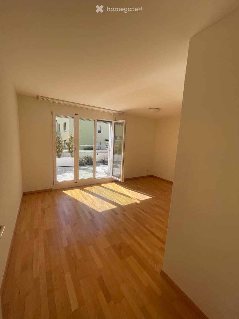 Empty room with wooden flooring and large sliding glass doors leading to a balcony area.