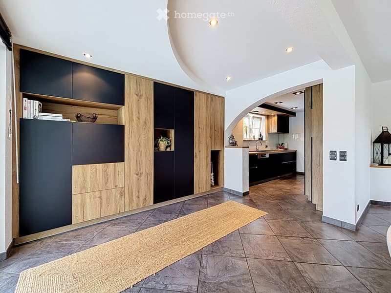 Modern kitchen with wooden and dark cabinets, a countertop, sink, and a small plant on a shelf.