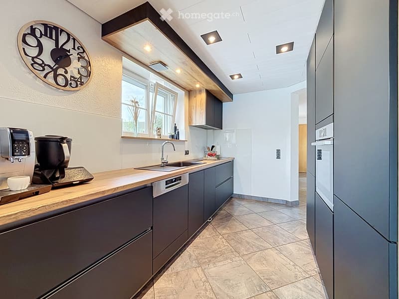 Modern kitchen with wooden countertops, stainless steel appliances, and built-in cabinets.