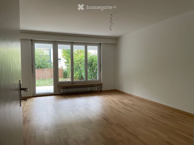 Empty room with wooden flooring, large windows, and a radiator beneath them. No furniture or equipment present.