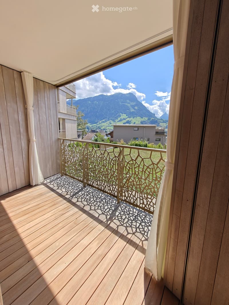 Balcony with wooden decking, decorative metal railing, and scenic mountain view.
