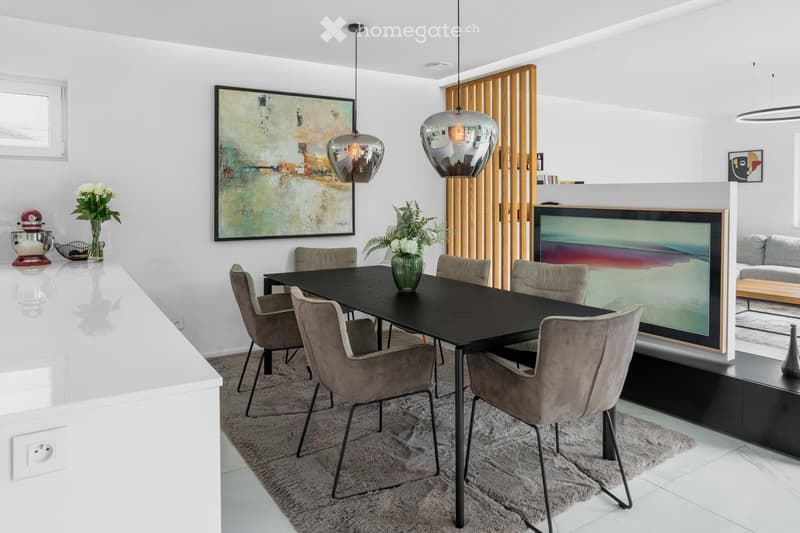 Modern dining and living area with a black dining table, six chairs, a sofa, a large screen, and decorative vases.