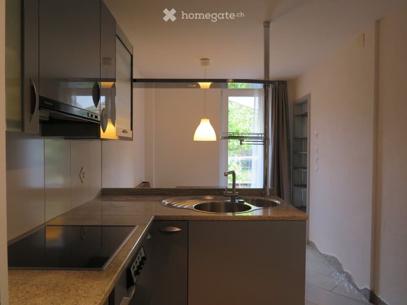 Modern kitchen with granite countertops, stainless steel sink, built-in oven, and pendant lighting.