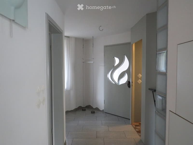 Empty hallway with tiled floor, white walls, and several doors, including one with a modern decorative handle design.