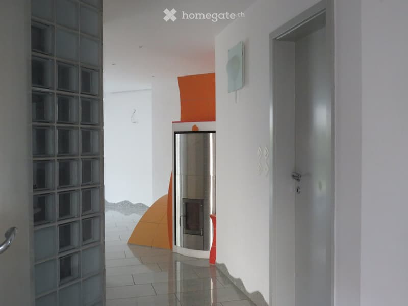 Modern hallway with white walls, tiled floor, and a built-in fireplace unit with an orange accent. Features glass-paneled doors and decorative wall art.
