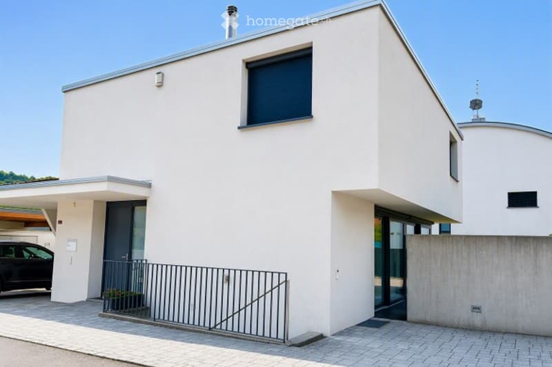 Modern two-story house with white exterior, large windows, garage, and parking area.
