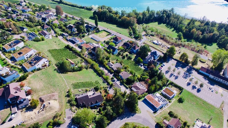 Aerial view of a residential area with multiple houses, green spaces, and a nearby body of water.