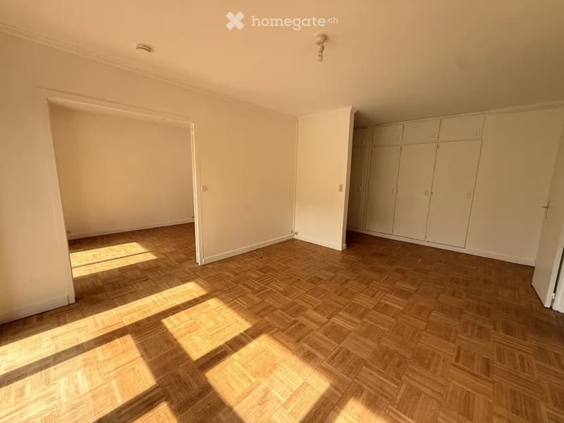 Empty room with wooden parquet flooring, white walls, and built-in wardrobes. No furniture or personal items present.