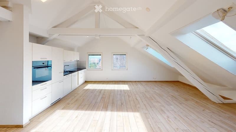 Bright, modern kitchen with white cabinets, a blue oven, and wooden flooring. Features skylights and large windows for natural light.