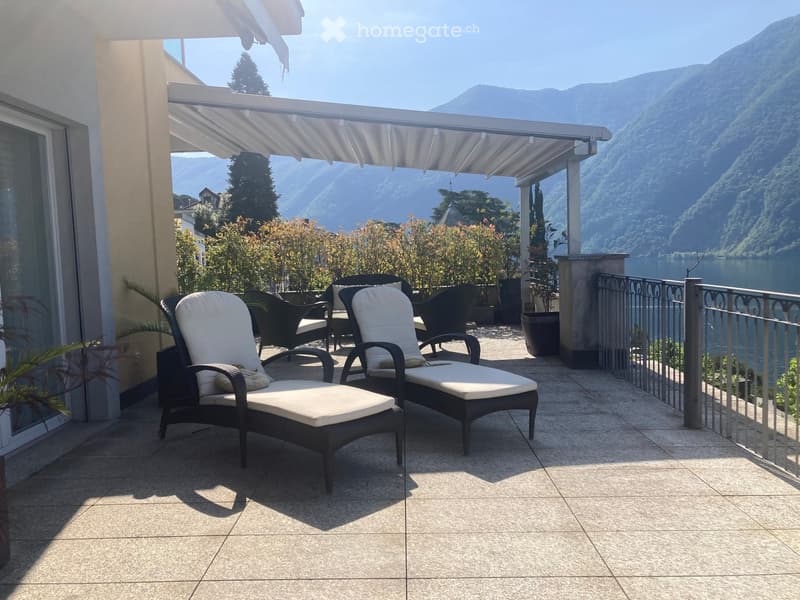 Balcony with lounge chairs, a table, and a scenic mountain and lake view.