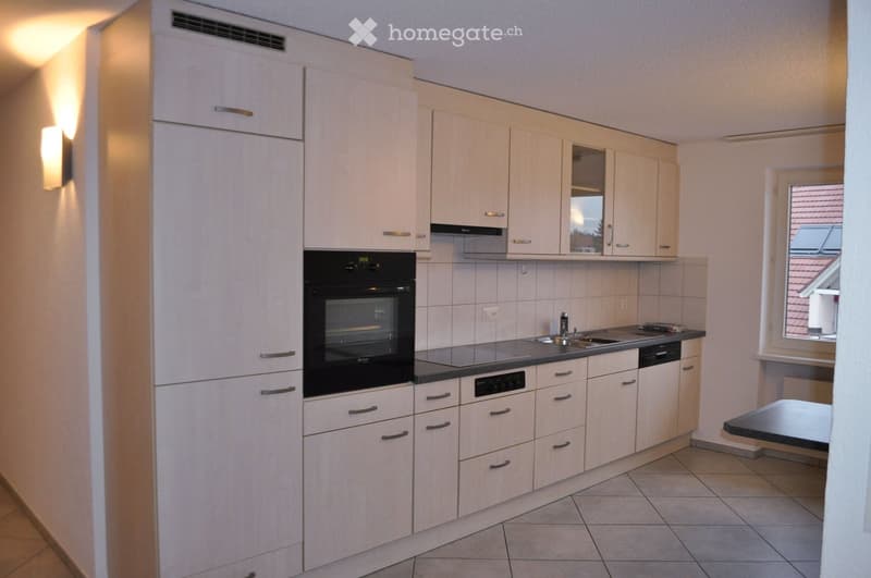 Modern kitchen with white cabinets, black oven, stainless steel sink, and tiled floor.
