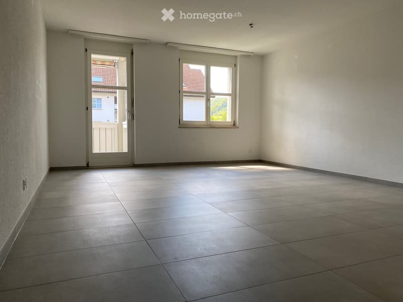 Empty room with tiled floor, white walls, large window, and sliding glass door leading outside.