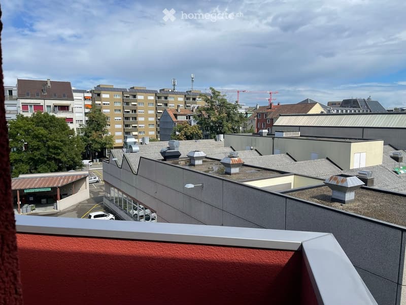 balcony with railing, city view, several buildings with trees