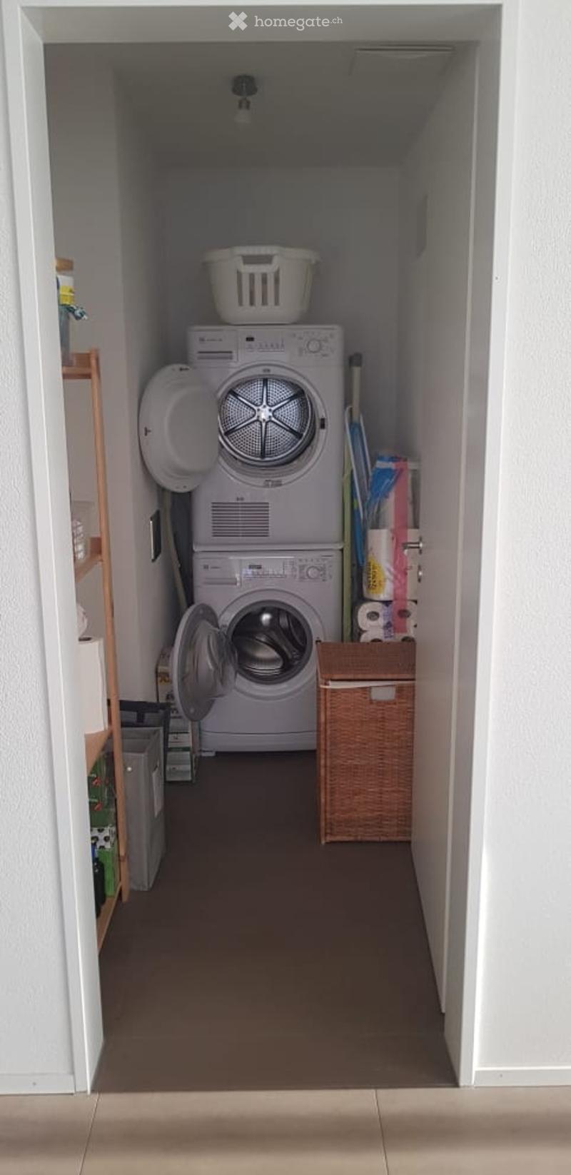 Laundry room with a washing machine, dryer, laundry basket, shelf, and wicker basket.