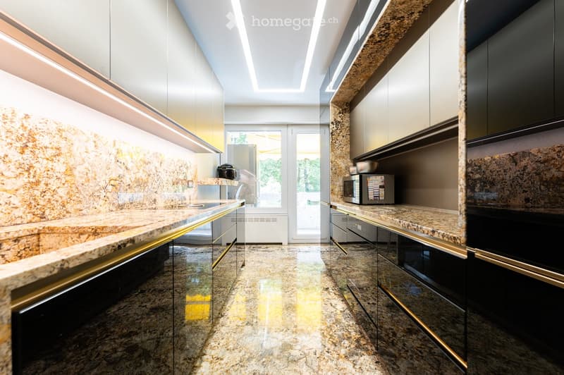 Modern kitchen with granite countertops, sleek black cabinets, and built-in appliances. Features a large window and a polished marble floor.