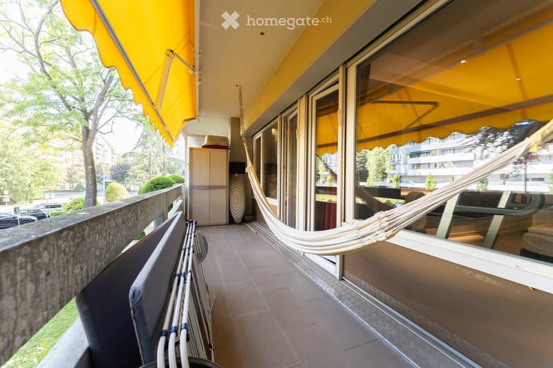 Balcony with yellow awnings, tiled floor, hammock, and a small cabinet.