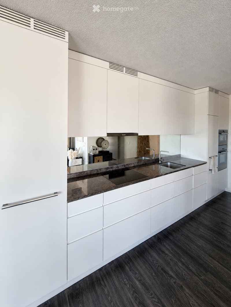 Modern kitchen with white cabinets, dark countertops, and stainless steel appliances.