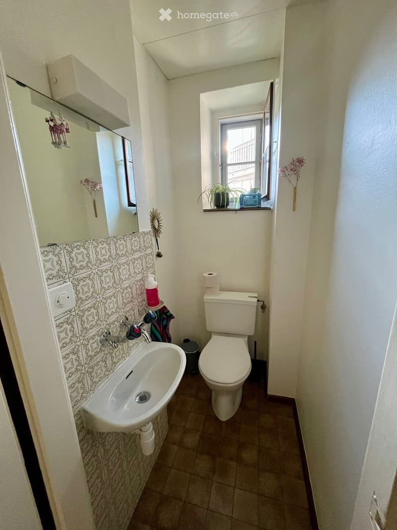 tiled floor, white sink, white toilet, mirror, window, power outlet