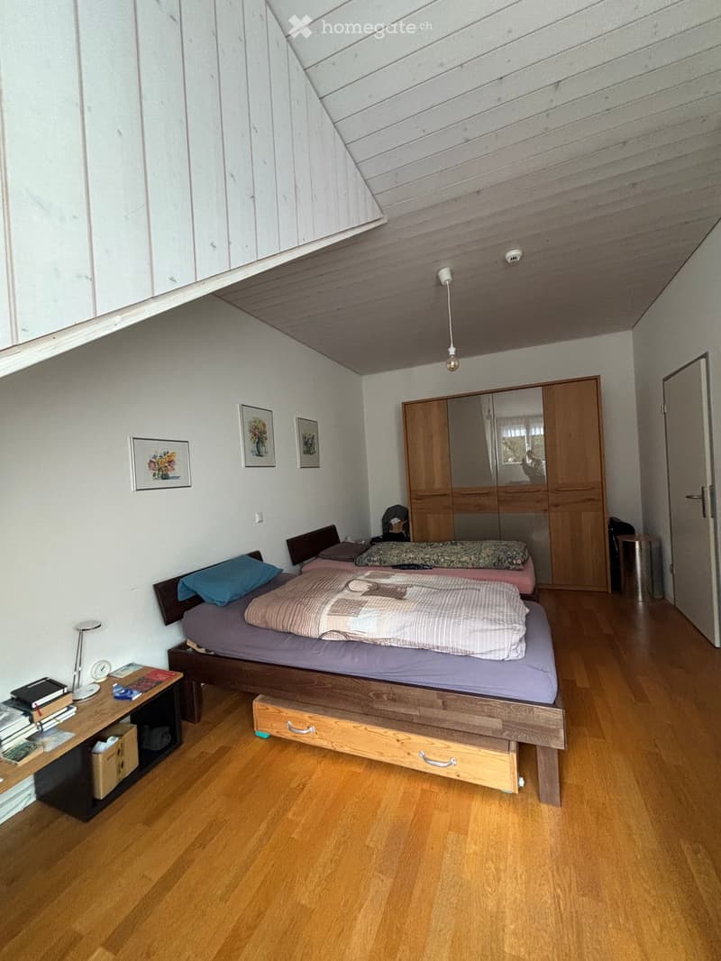 Bedroom with wooden floor, two beds, wooden nightstands, wooden cabinet, white walls, three picture frames, and a lamp