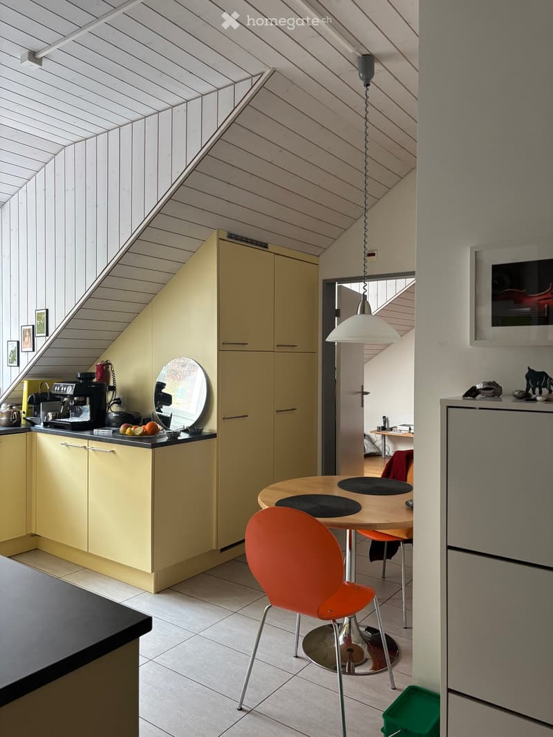 kitchen with yellow cabinets, black countertop, round table, orange chair, round mirror, hanging lamp