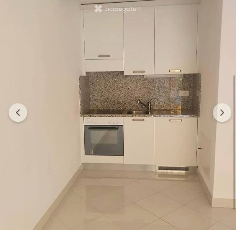 Modern kitchen with white cabinets, granite countertop, stainless steel sink and faucet, and built-in oven.