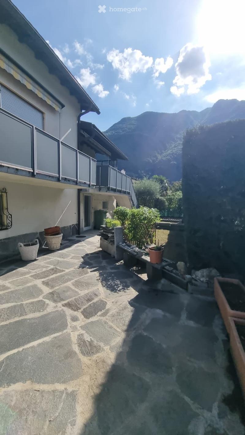 Courtyard with stone pavement, potted plants, and a view of mountains in the background.