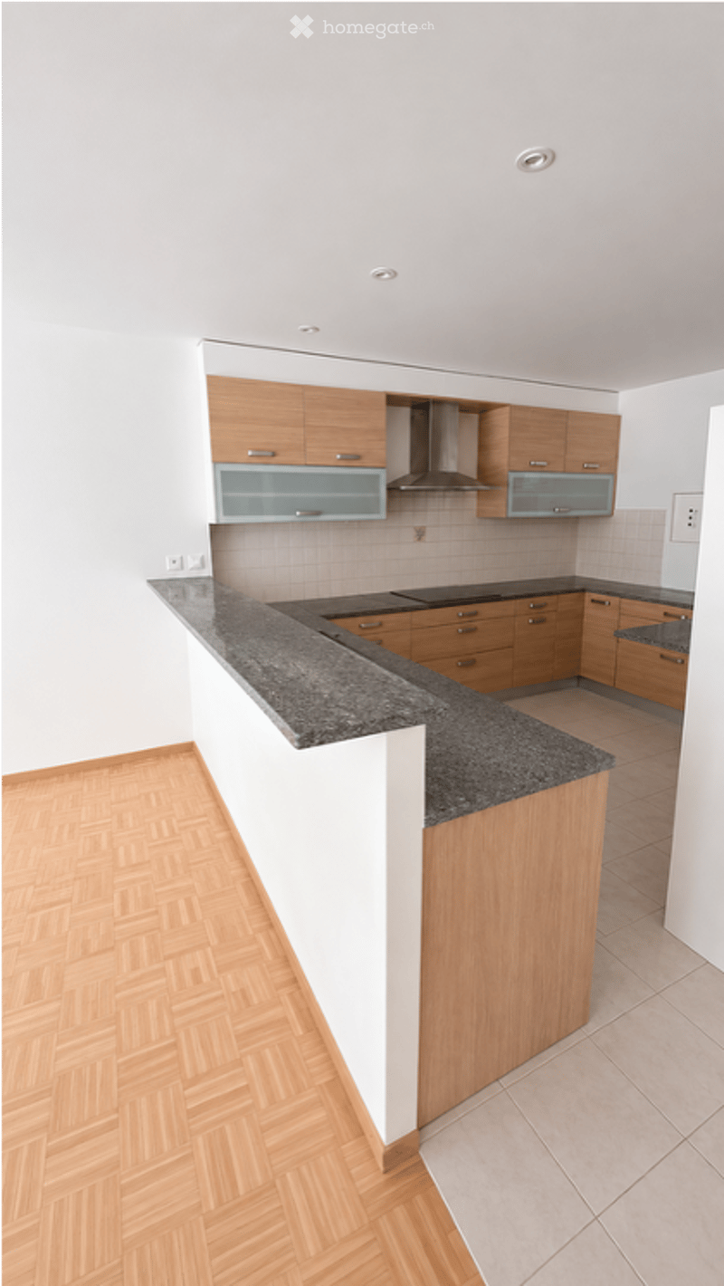 Modern kitchen with light wooden cabinets, granite countertop, and built-in appliances including a stove and range hood.