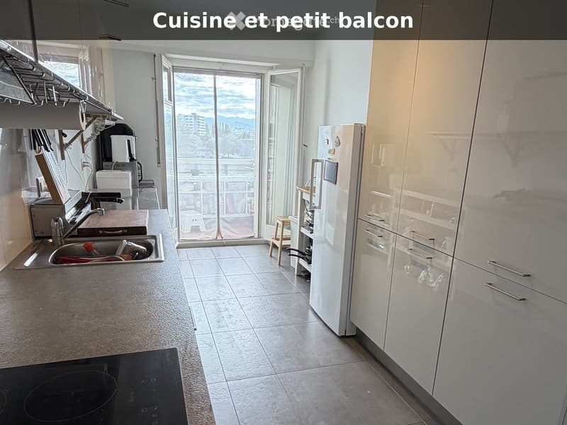 Modern kitchen with white cabinets, stainless steel sink, refrigerator, and a small balcony with a view.