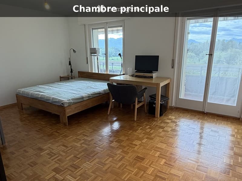 Bedroom with wooden floor, large windows, bed, desk, chair, and screen.