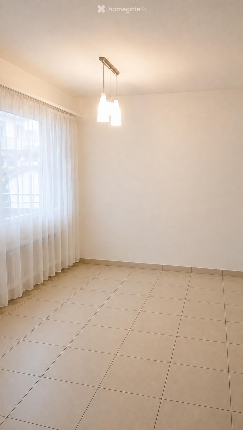 Empty room with beige tiled floor, white walls, large window with white curtains, and a modern pendant light fixture.