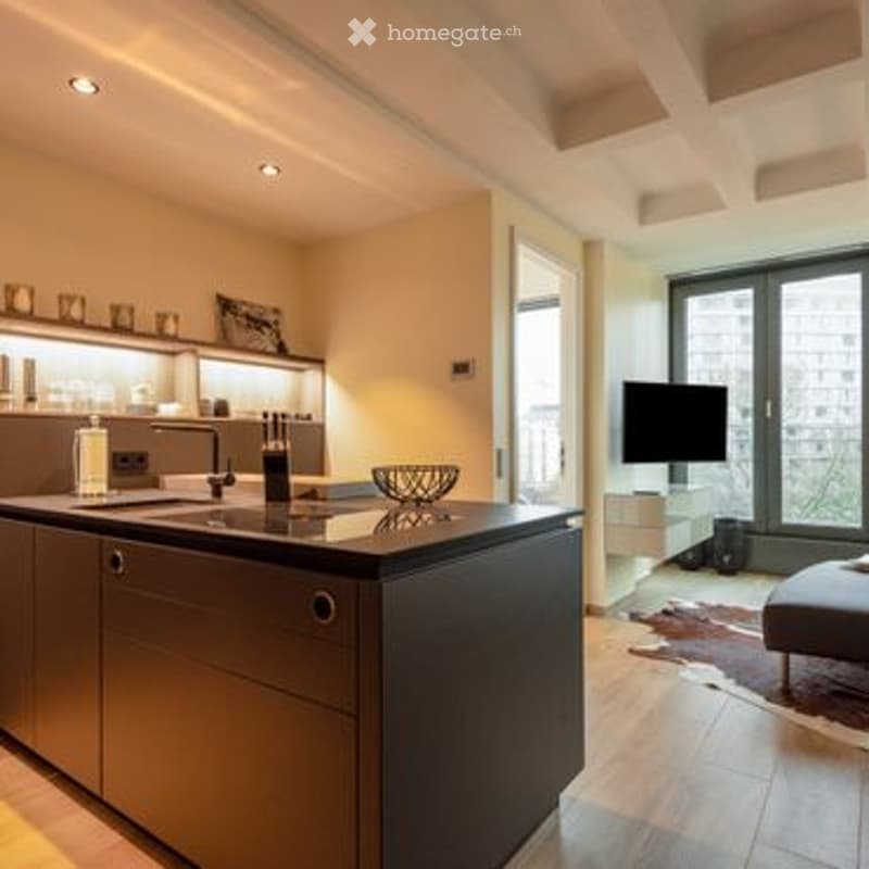 Modern kitchen with a central island, stainless steel appliances, and a sleek design. The space features a large window with a view, a television, and contemporary furniture.