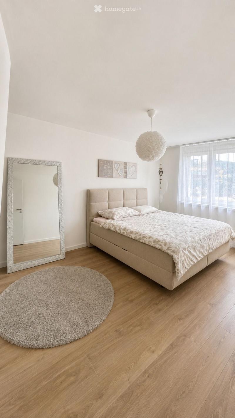 Modern bedroom with a large bed, round shaggy rug, large mirror, and wall decor featuring the word "LIVE".