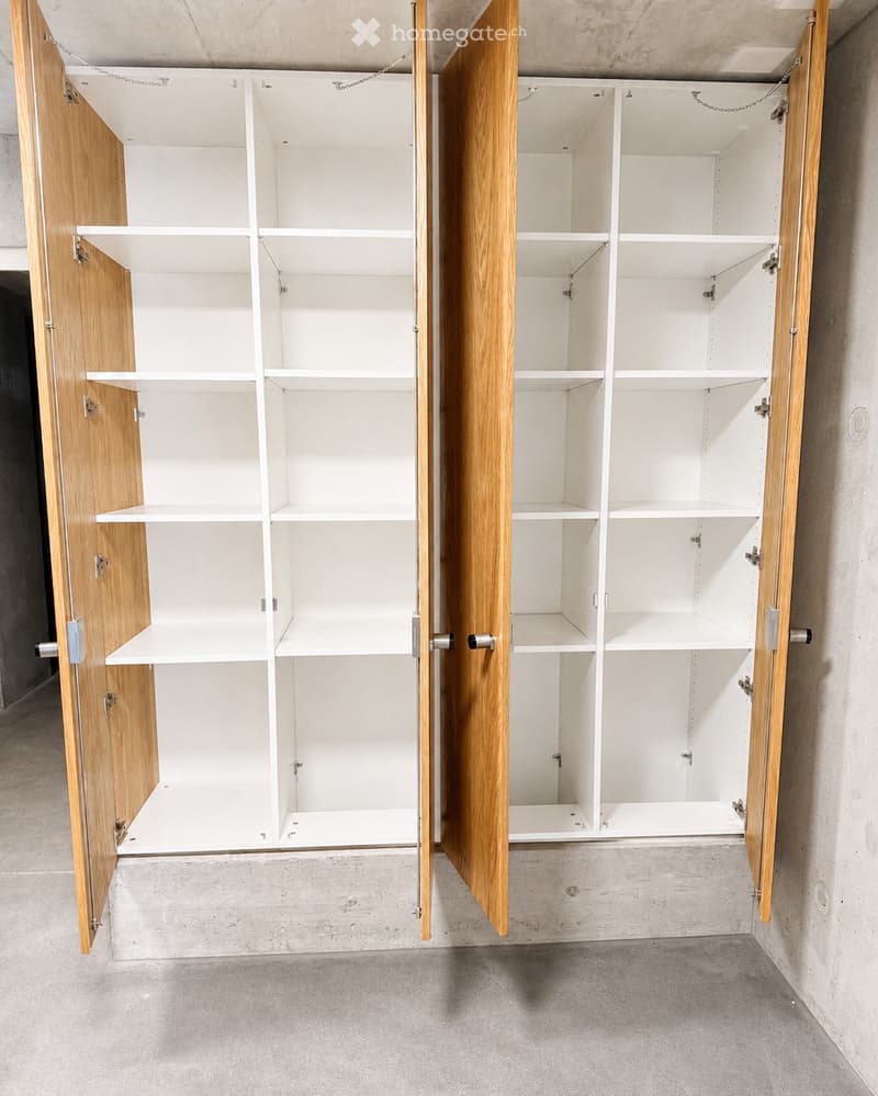 Empty room with built-in wooden cabinets and white shelving units, no furniture or items present.