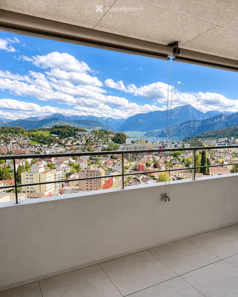 Balcony with modern railings, tiled floor, and expansive view of a town and mountains.