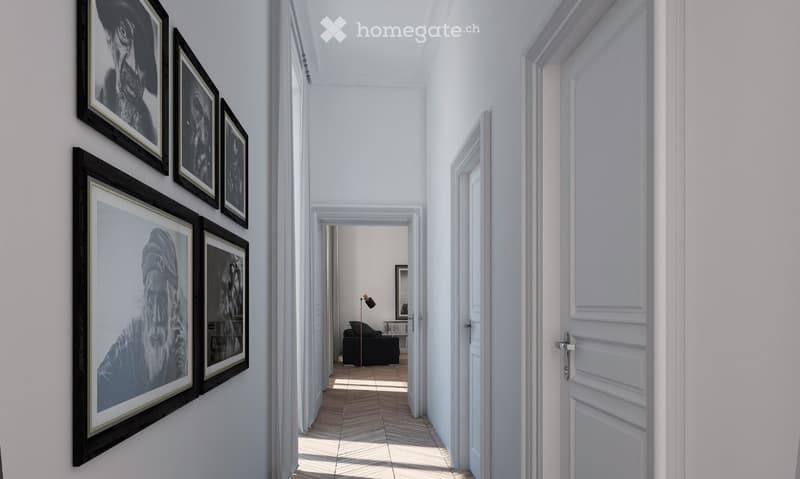 A bright, white-walled hallway with a wooden floor, featuring framed black-and-white artwork on one wall and a closed white door on the other. A small room with a sofa and a floor lamp is visible at the end of the hallway.
