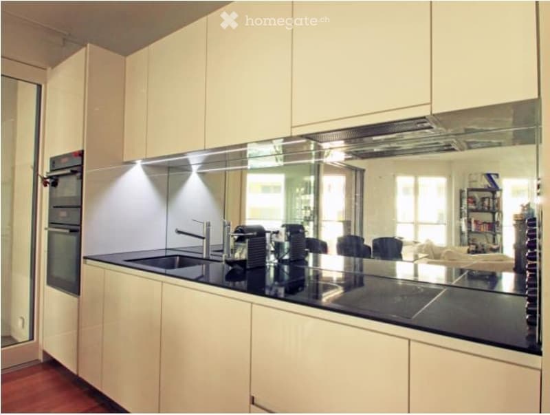 Modern kitchen with white cabinets, black countertop, stainless steel appliances, and a sleek design.