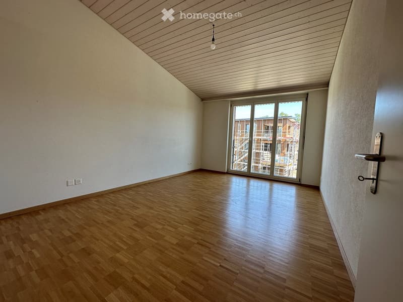 Empty room with wooden flooring, white walls, and a large sliding glass door leading to a balcony or outdoor area.