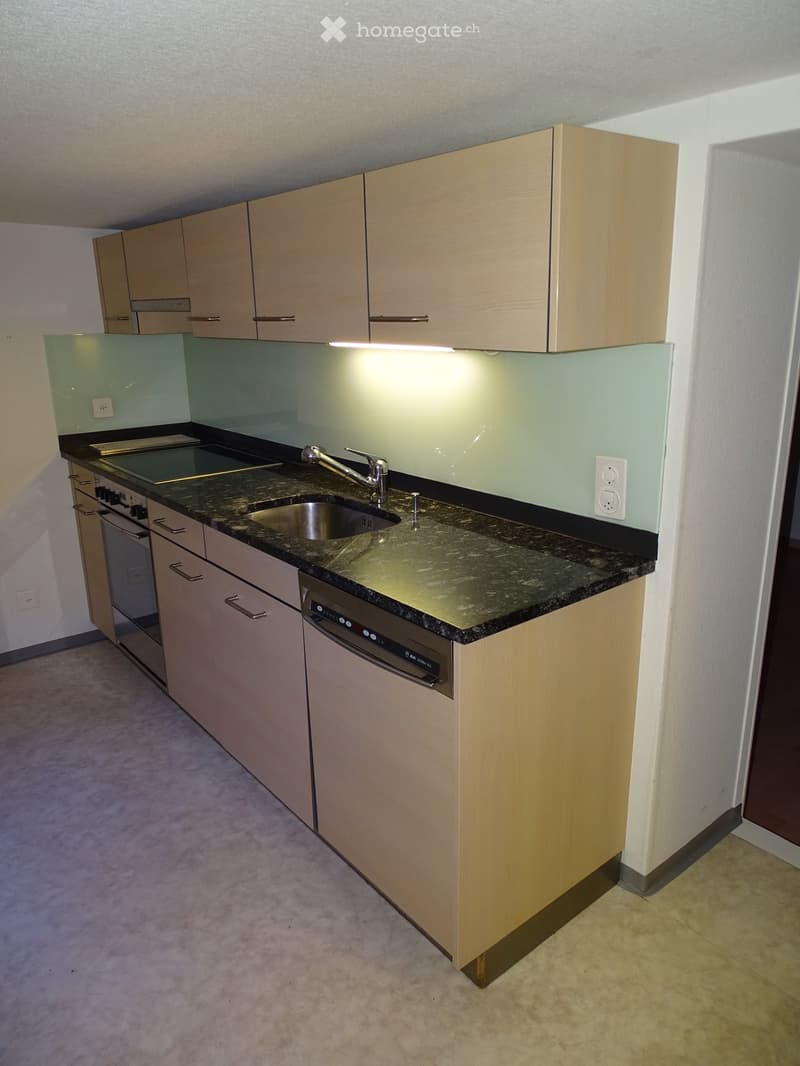Modern kitchen with light wood cabinets, granite countertop, stainless steel sink, and built-in dishwasher.