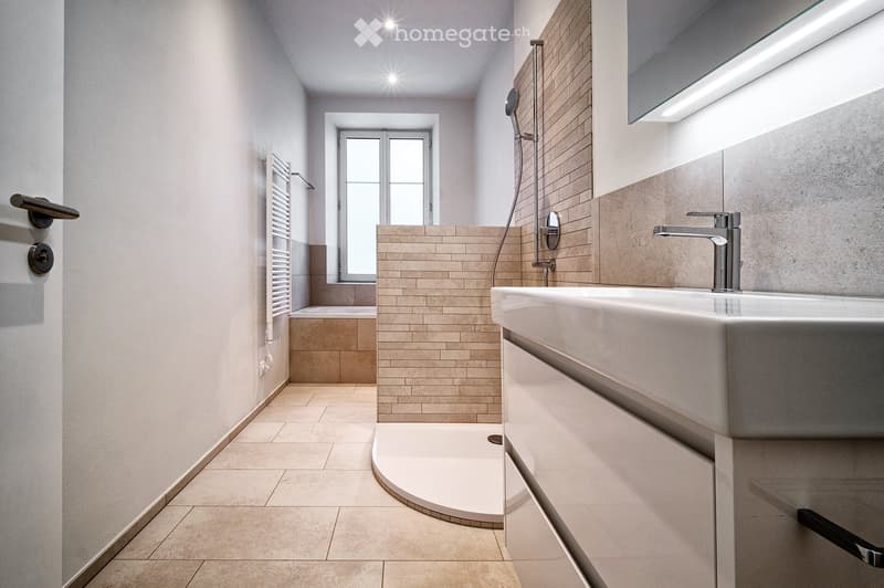 modern bathroom with white tiles, bathtub, shower, sink, and towel rack