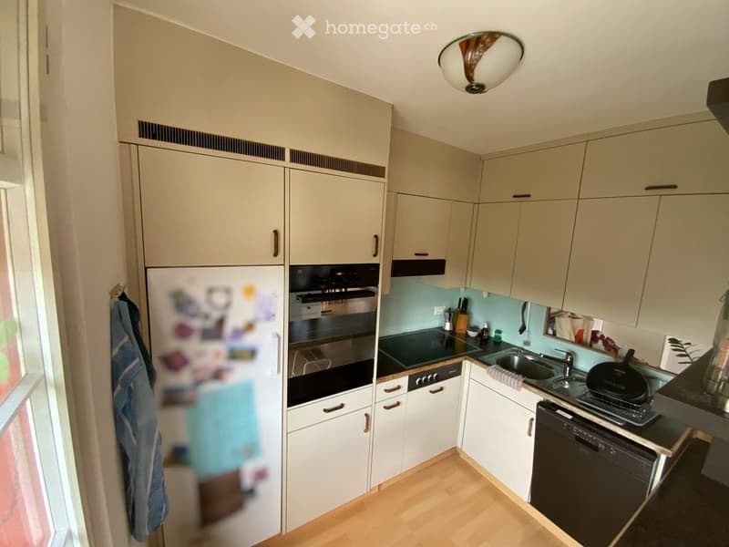 Modern kitchen with light-colored cabinets, stainless steel appliances, and a light blue backsplash. Features include a refrigerator, oven, dishwasher, sink, and countertop items.