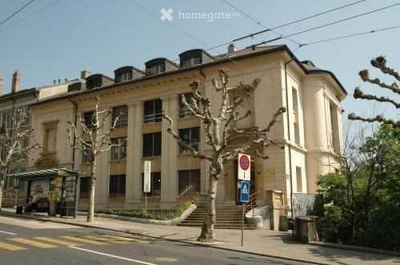 A multi-story building with a beige facade, decorative architectural elements, and balconies visible on the upper floors.