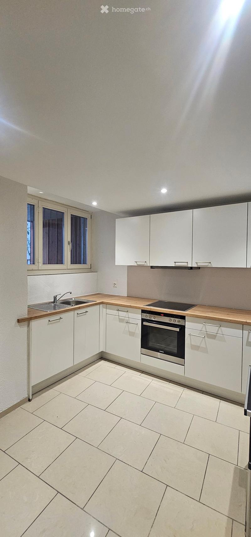 Modern kitchen with white cabinets, wooden countertop, stainless steel sink, and built-in oven.