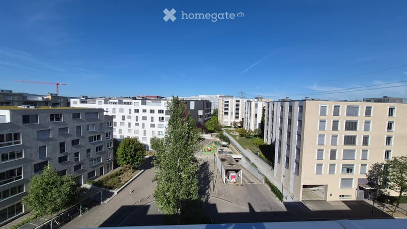 View of a modern residential complex with multiple apartment buildings, green spaces, and a playground area.