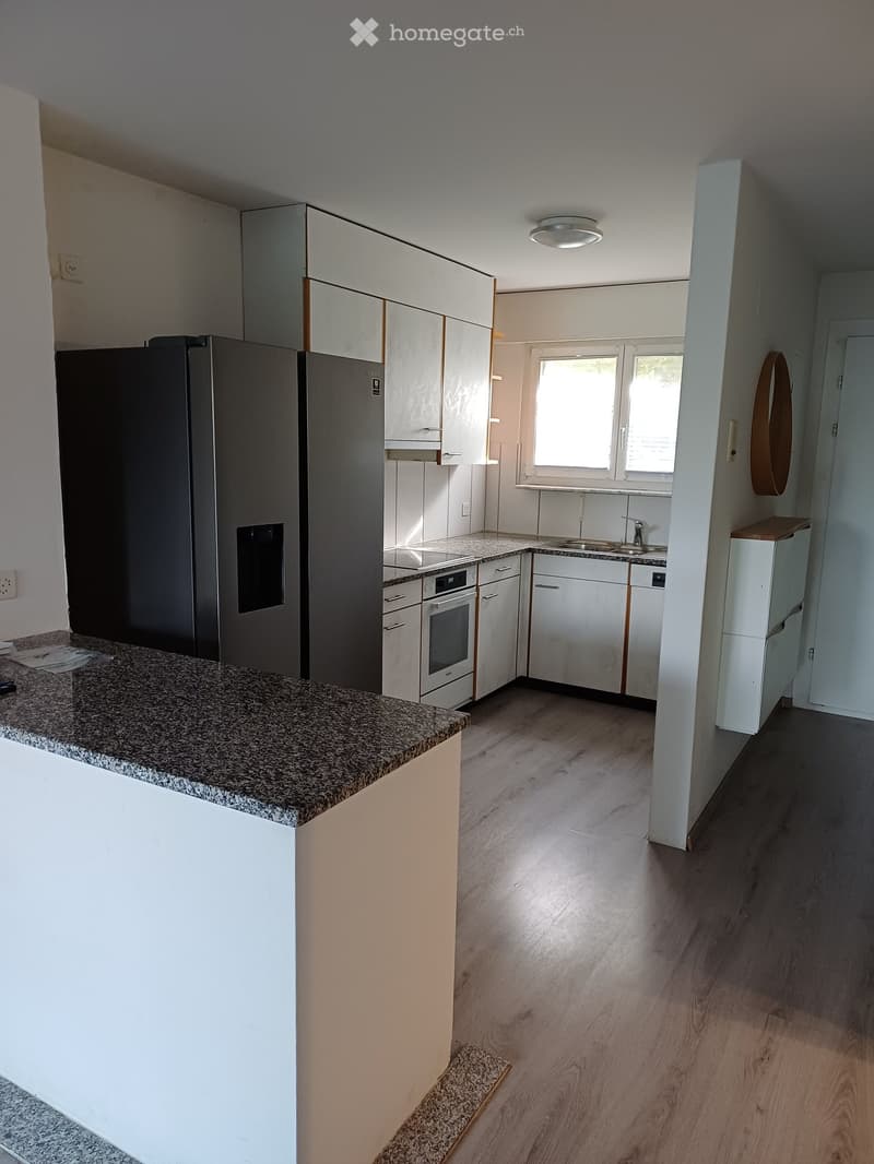 Modern kitchen with white cabinets, stainless steel appliances, granite countertop, and wooden flooring.