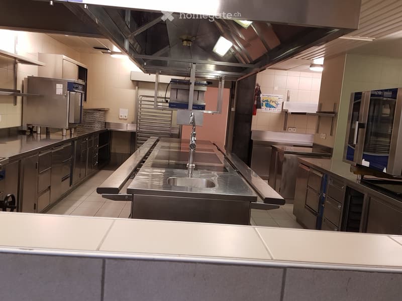 Commercial kitchen: stainless steel counters, gas range, extractor fan, stainless steel cabinets, ovens